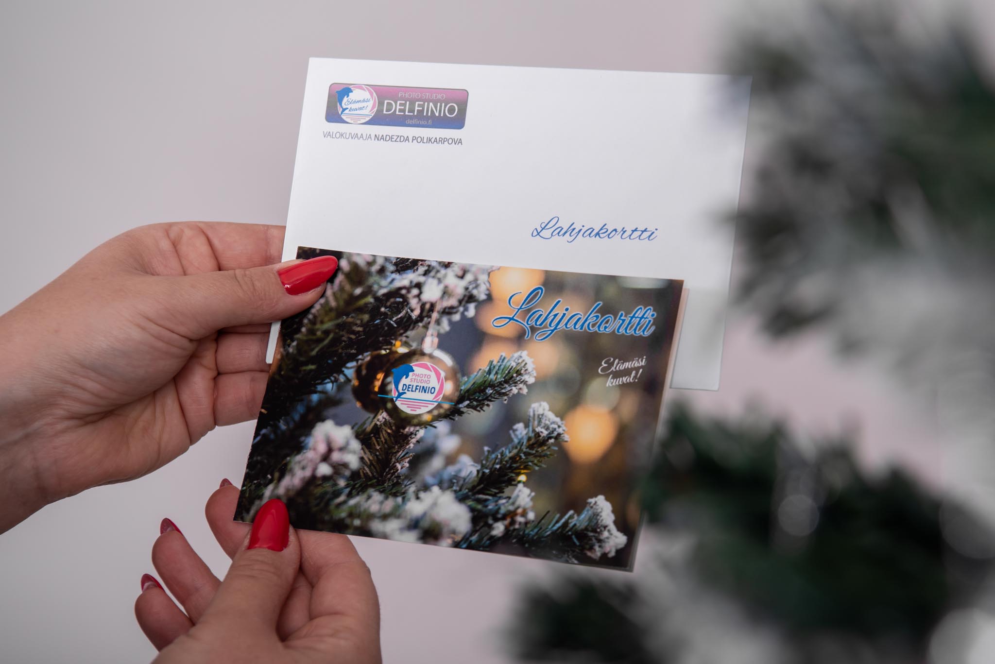 Valokuvaaja Salo pitelee lahjakorttia ja kuorta kädessään – Photo Studio Delfinio, valokuvauslahja.