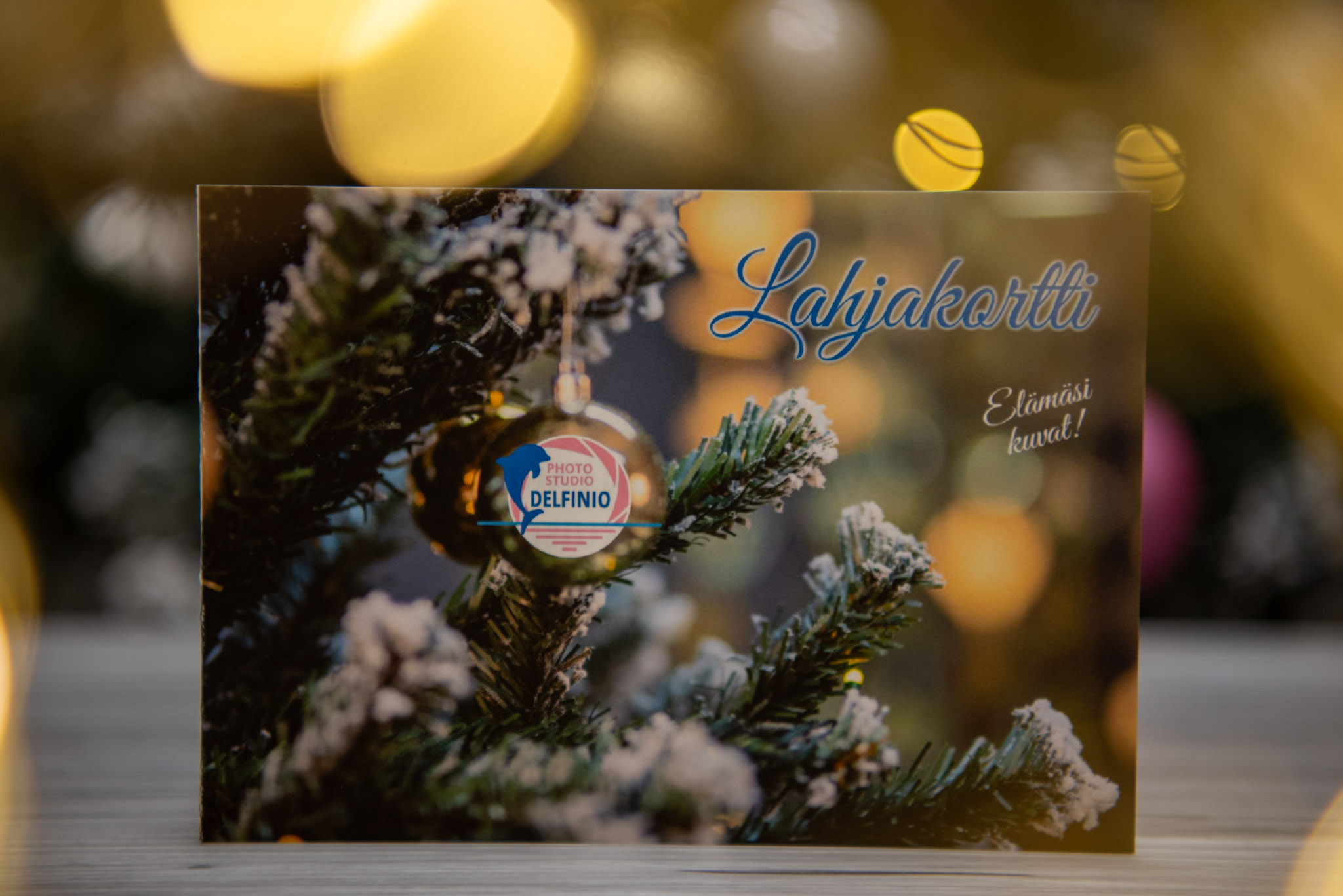 Joululahjakortti valokuvaukseen, valkoisella filtteri-efektillä ja kultaisilla valopilkuilla kuusen edessä – Photo Studio Delfinio, valokuvaaja Salo.