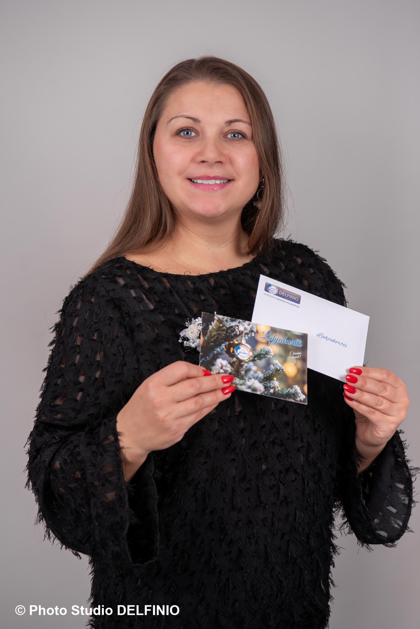 Valokuvaaja Salo pitelee lahjakorttia ja kuorta kädessä – portretti Photo Studio Delfiniosta, täydellinen valokuvauslahja.