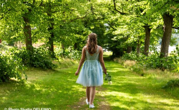 Rippikuvaus Teijon Ruukissa: nuori tyttö kävelee lipputietä pitkin sinisessä mekossa, kädessään ruusu. Valokuvaaja Salo, konfirmointikuvat Teijo.