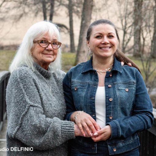 Kaksi naista seisoo puisella sillalla Fiskarsissa keväisessä maisemassa – lämmin ja iloinen hetki valokuvauksessa.