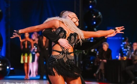 Tanssipari liikkeessä Latina SM -kilpailussa Salossa, taustalla yleisö ja odottavat parit.